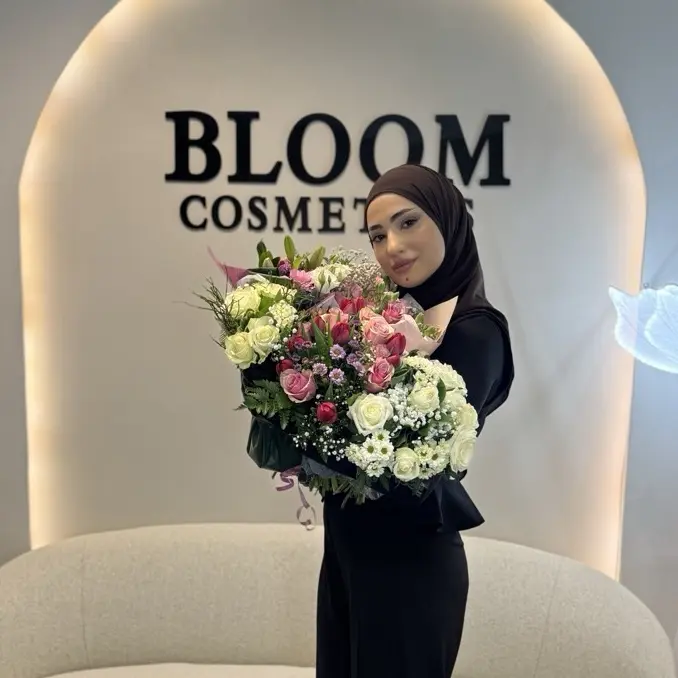 Gründerin von Bloom Cosmetics mit Blumenstrauß vor der Studiowand